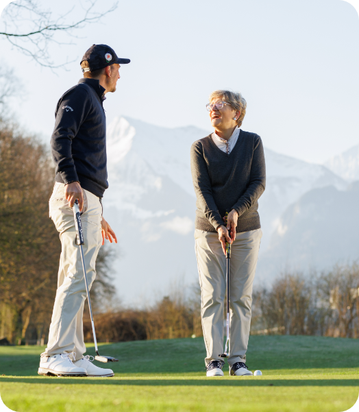 Two people on a golf course with a trainer